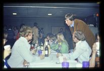 Photograph of group of individuals talking around table during 1976 Homecoming festivities